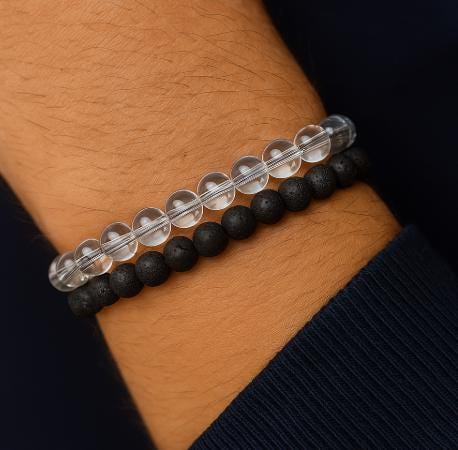 Two bracelets on a wrist, one black beaded and one clear beaded.