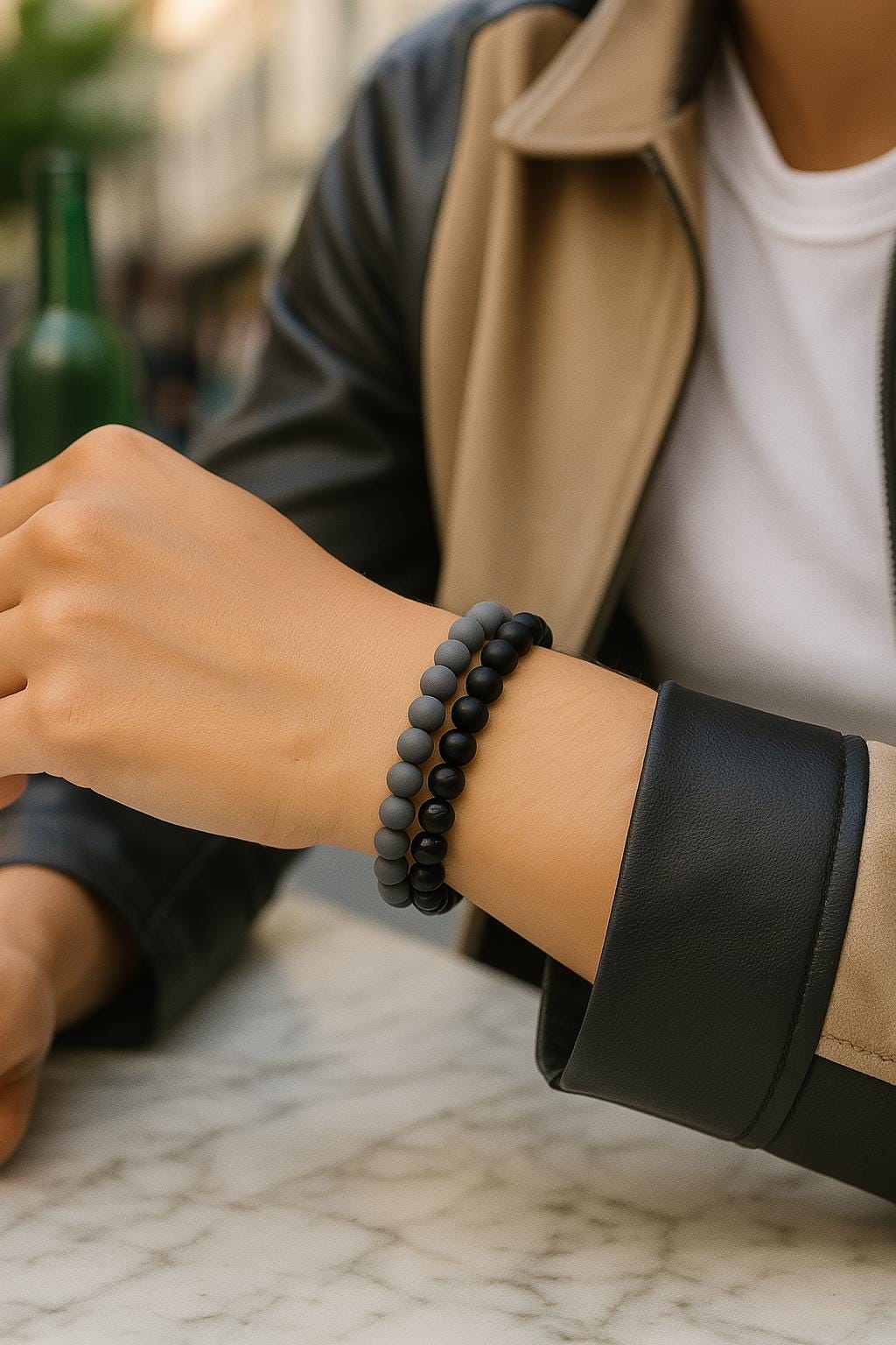 Person wearing a black beaded bracelet on a marble surface