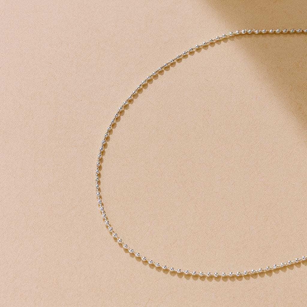 Delicate silver chain necklace on a beige background