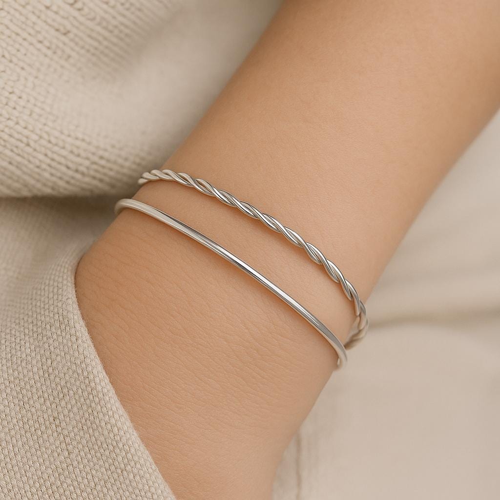 Silver bracelet on a wrist with a neutral background