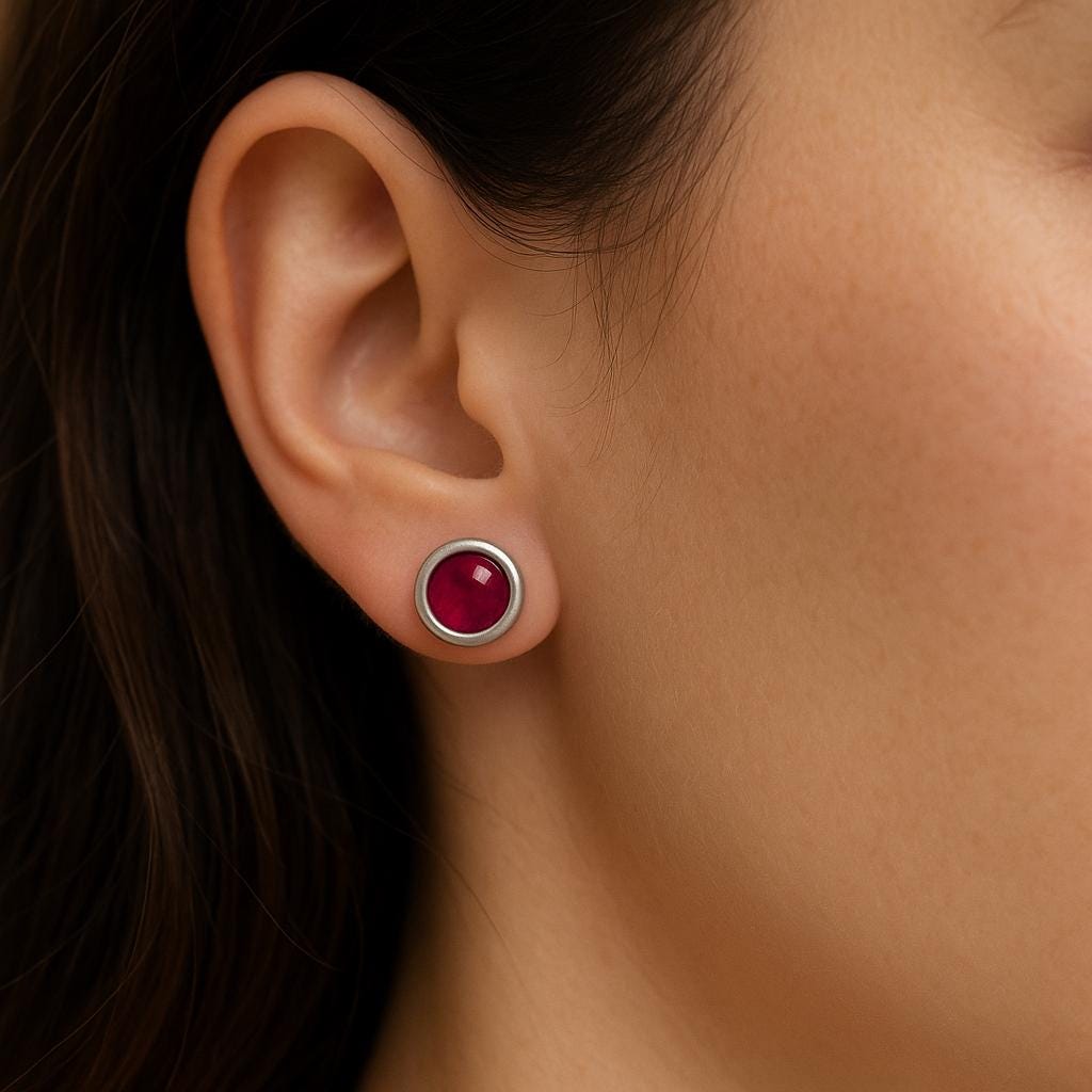 Close-up of an ear wearing a red gemstone earring. July Birthstone jewelry gift.