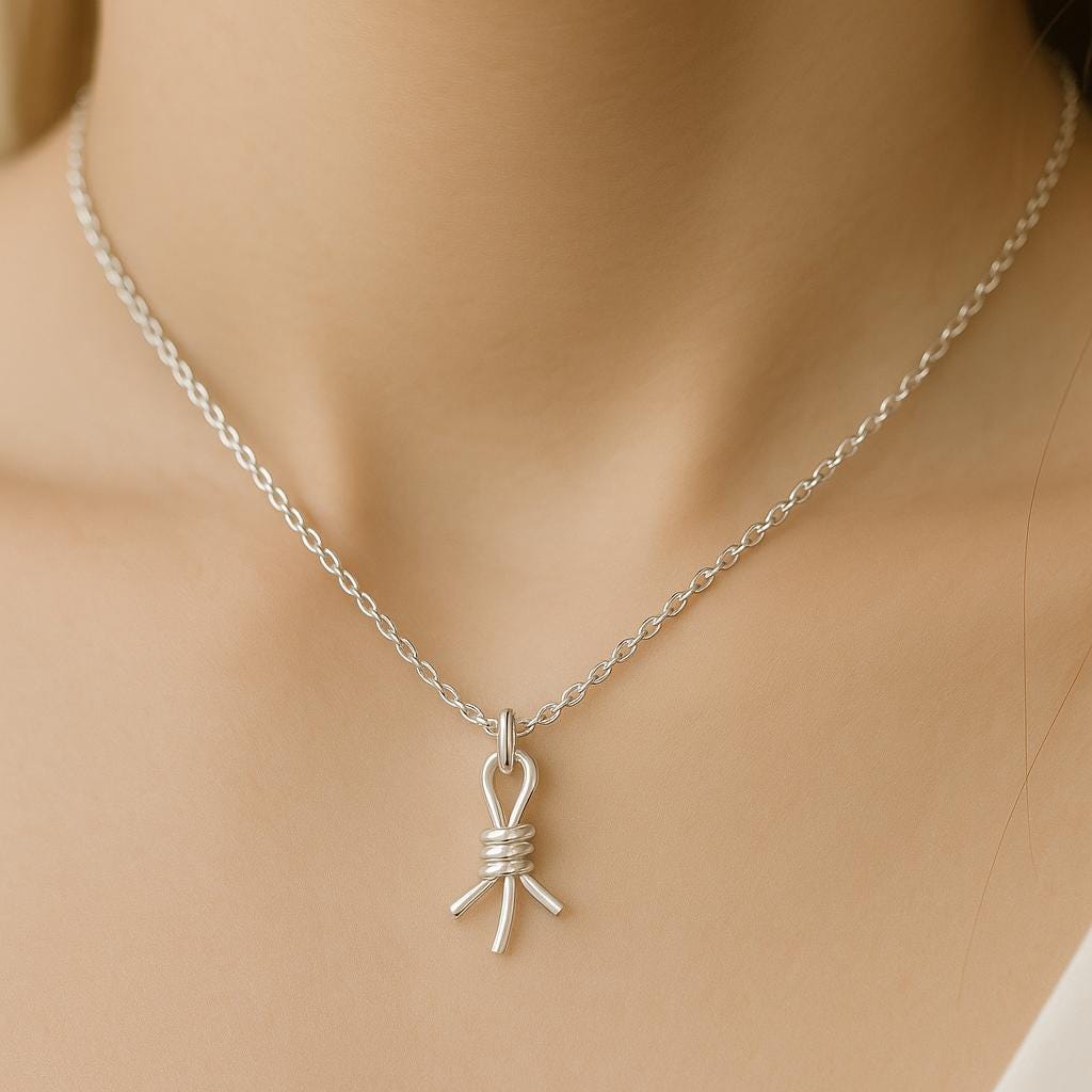 Silver necklace with a bow pendant on a mannequin