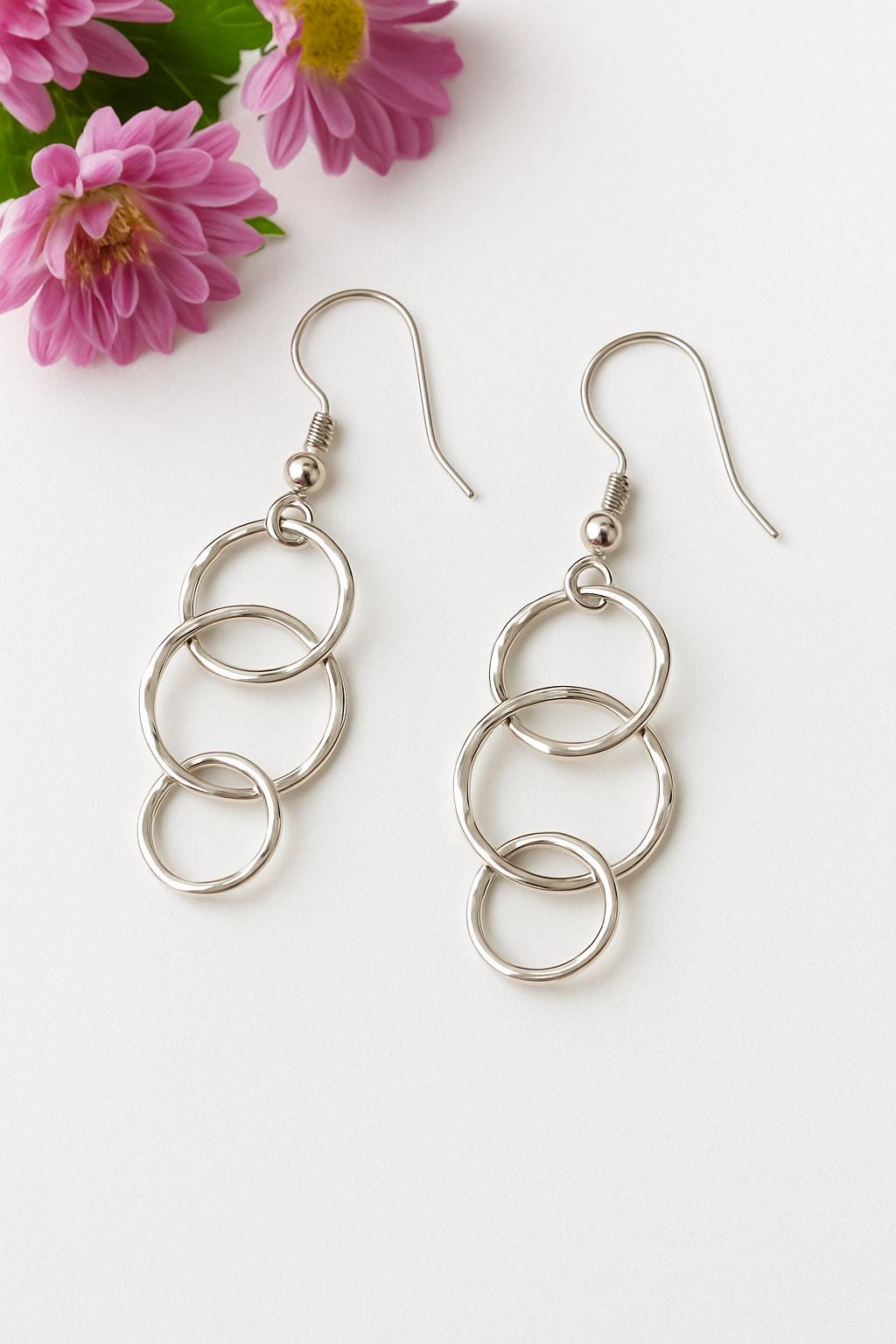 Silver chain earrings on a white background with pink flowers.