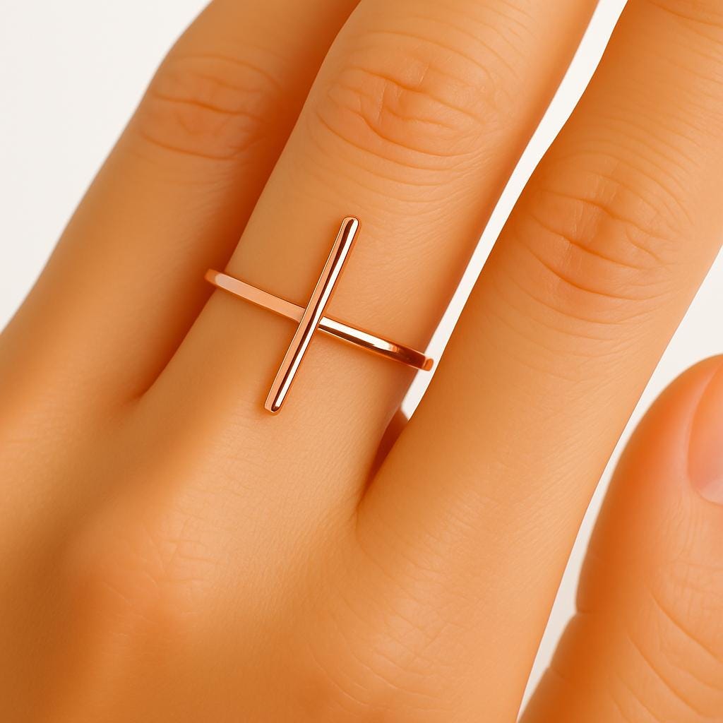 Rose gold ring on a person's finger with a plain background