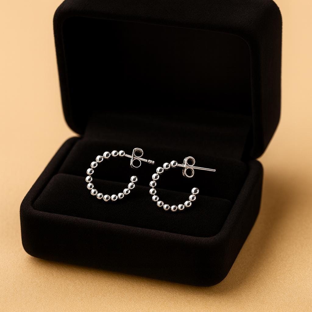 Silver hoop earrings in a black jewelry box on a beige background