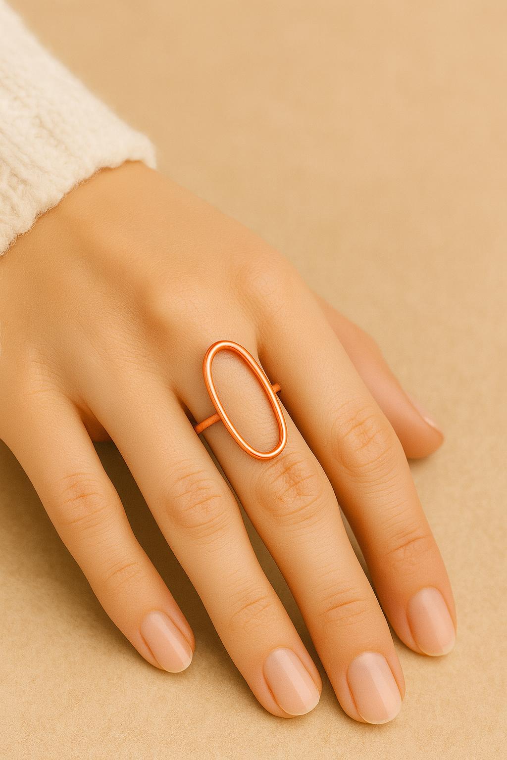 Hand wearing a gold ring on a beige background