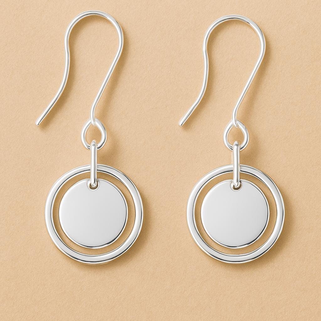 Silver earrings with circular designs on a beige background