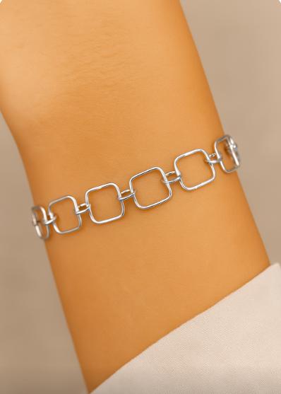 Silver chain bracelet on a wrist against a beige background