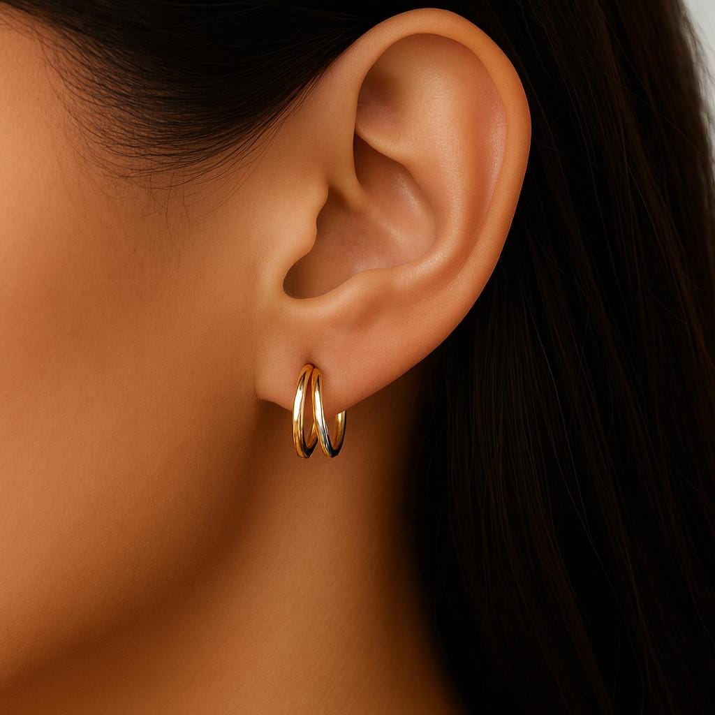 Close-up of an ear wearing a gold hoop earring with a blurred background