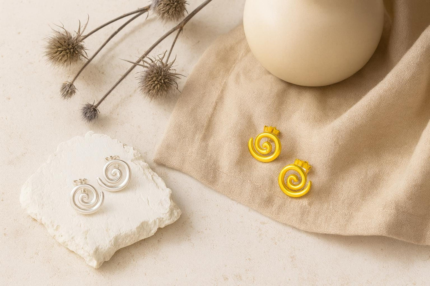 Pair of spiral-shaped earrings on a beige fabric with a neutral background