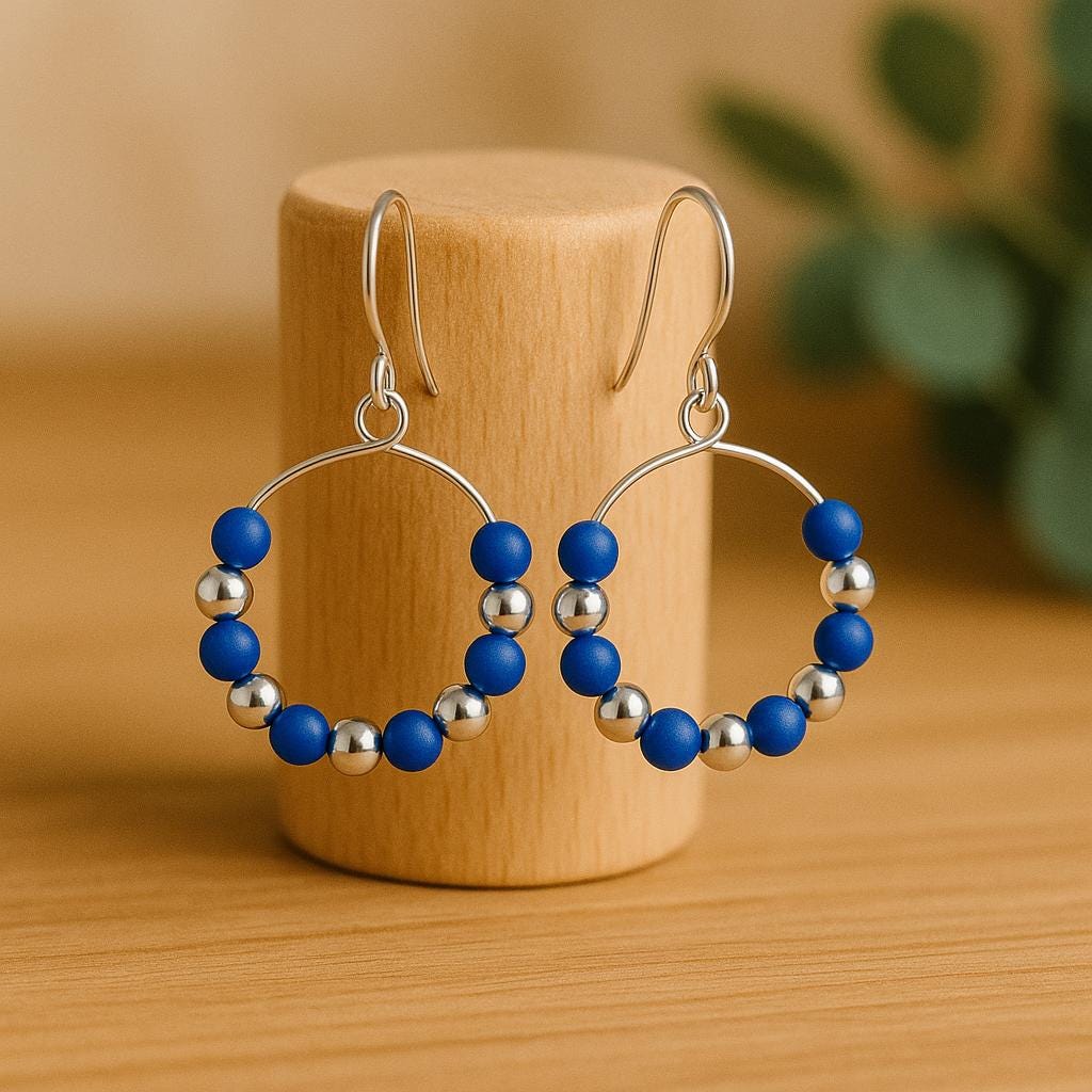 Hoop earrings with blue and silver beads on a wooden stand.