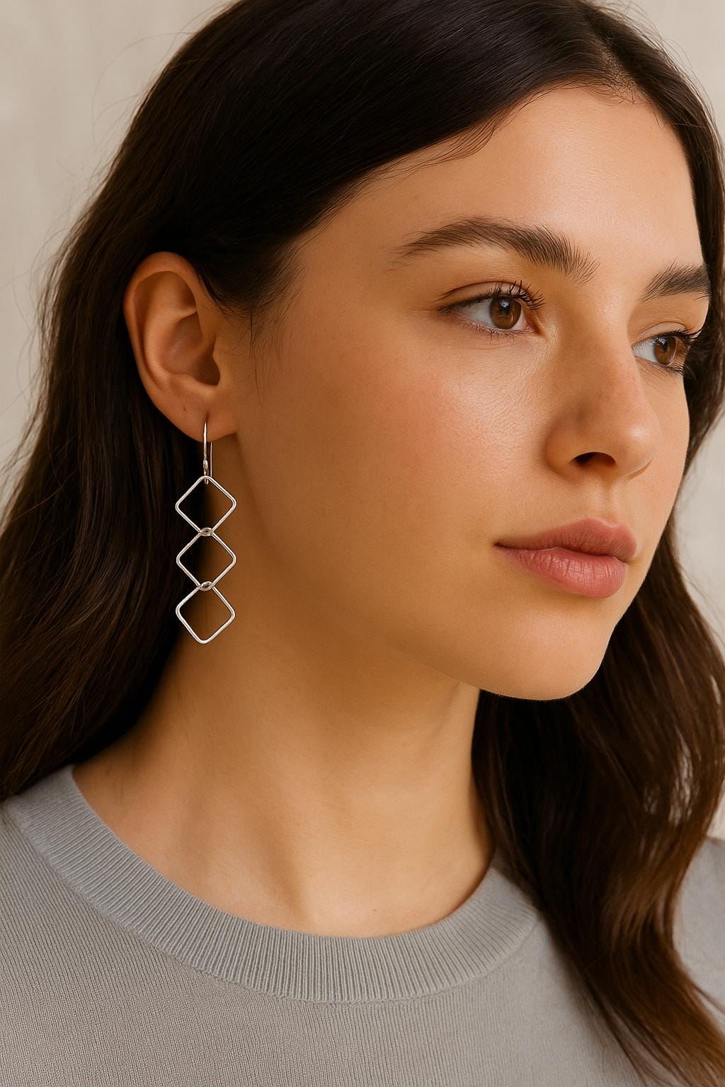 Woman wearing a pair of silver earrings with a neutral background
