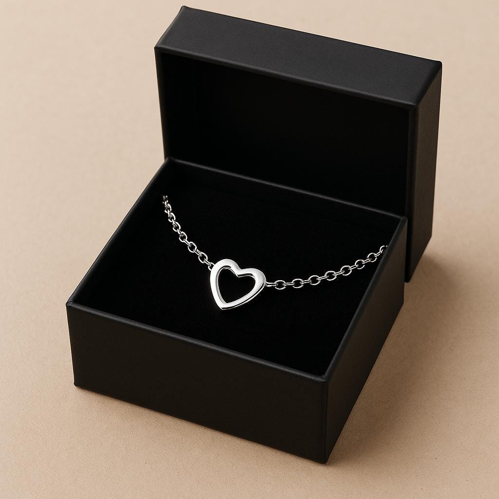 Silver heart-shaped bracelet in an open black jewelry box on a beige background