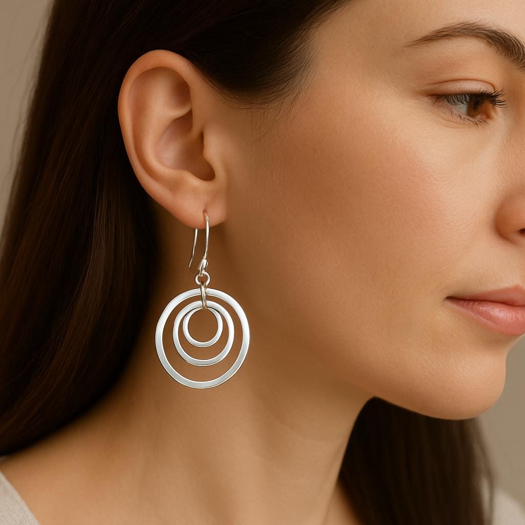 Close-up of a woman wearing silver circular earrings against a neutral background