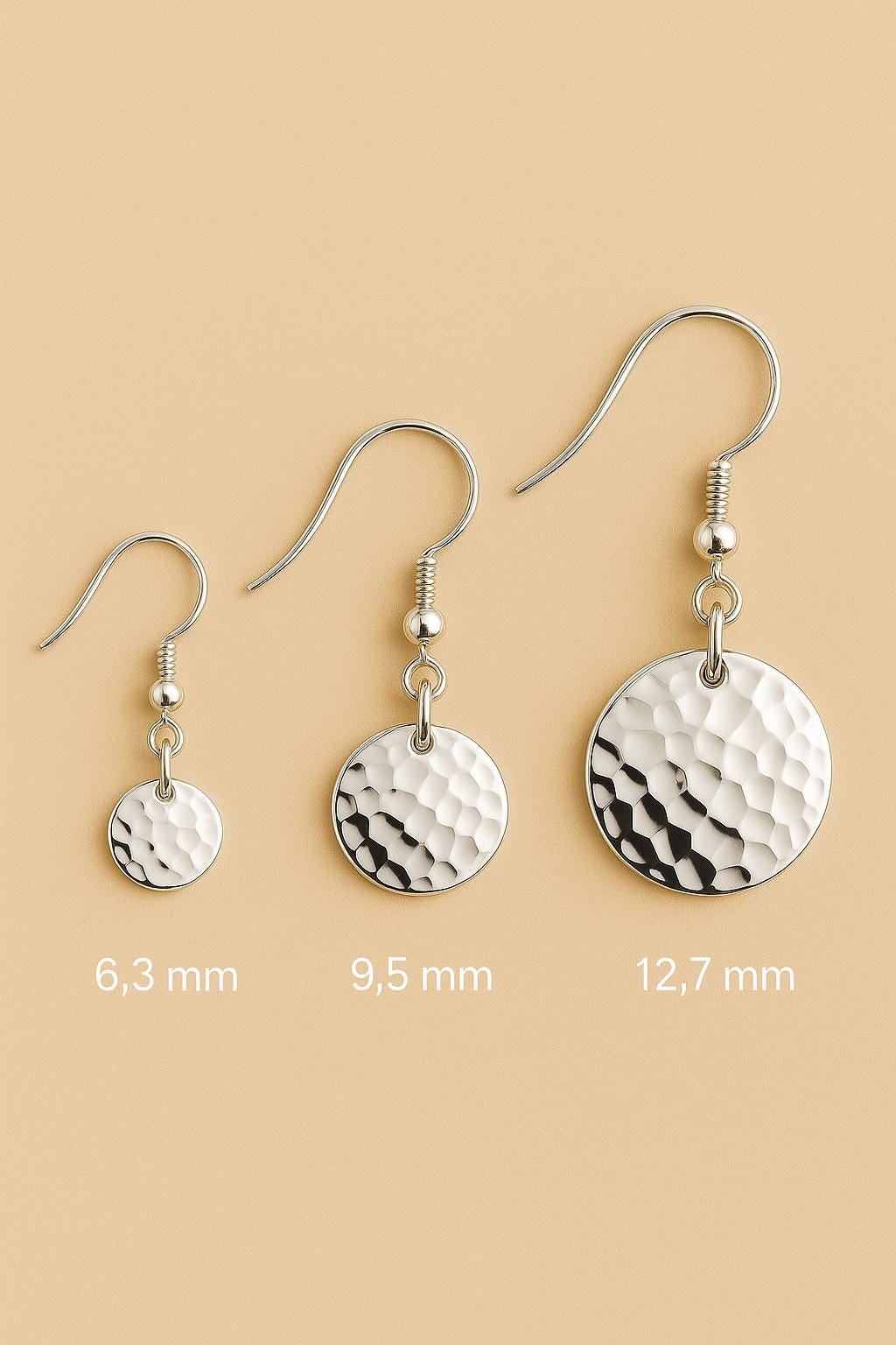 Three pairs of silver earrings with different disc sizes on a beige background