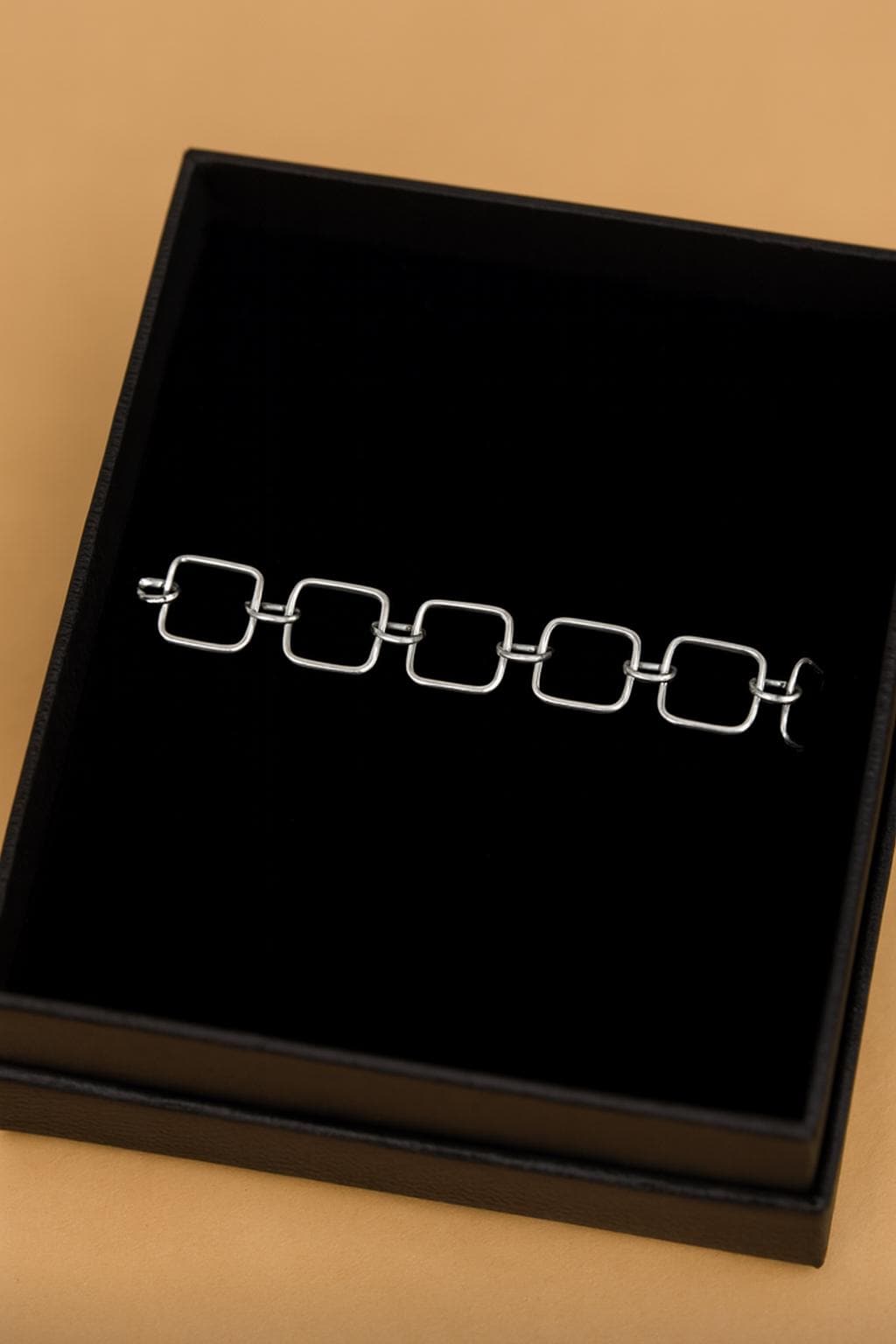 Silver bracelet on a black display box with a beige background