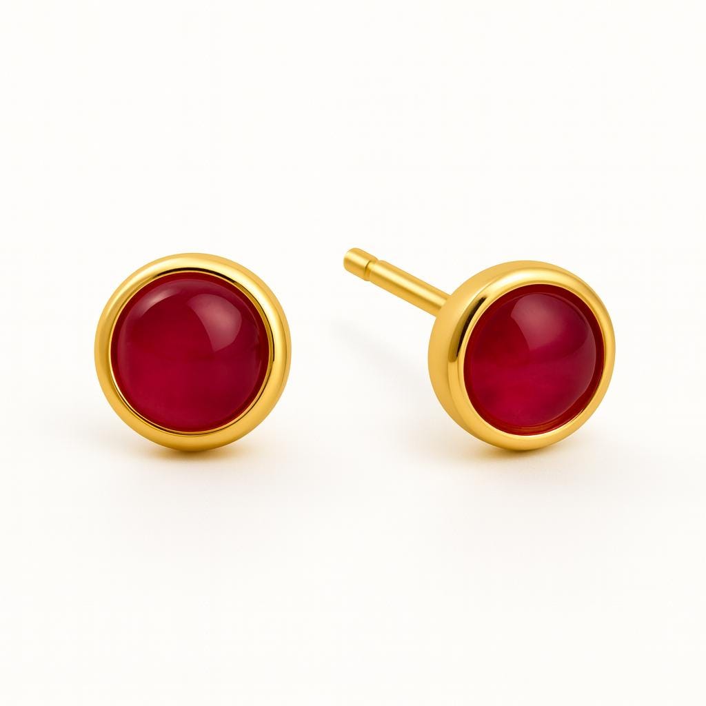 Gold earrings with red gemstones on a white background