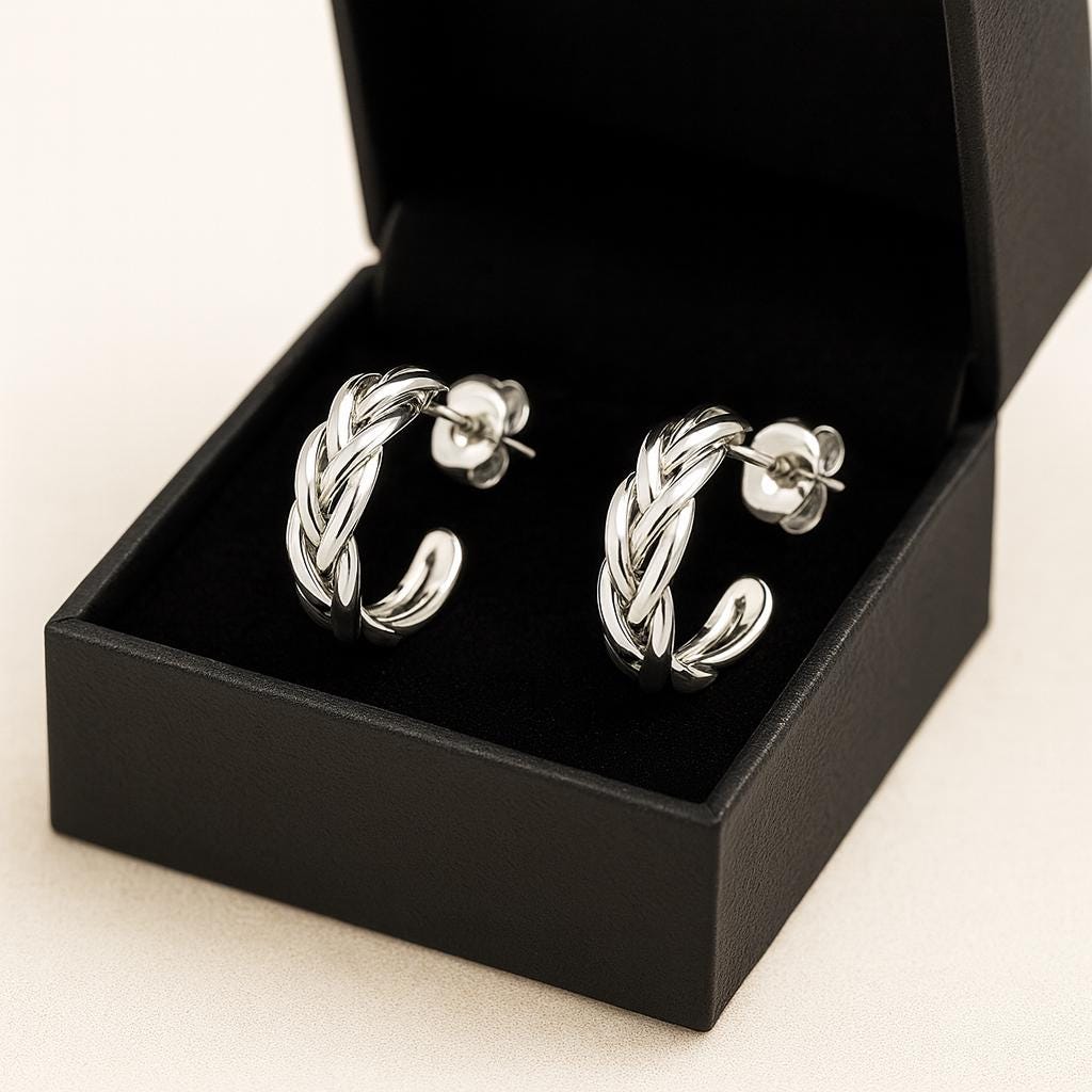 Silver hoop earrings in a black jewelry box on a light beige background