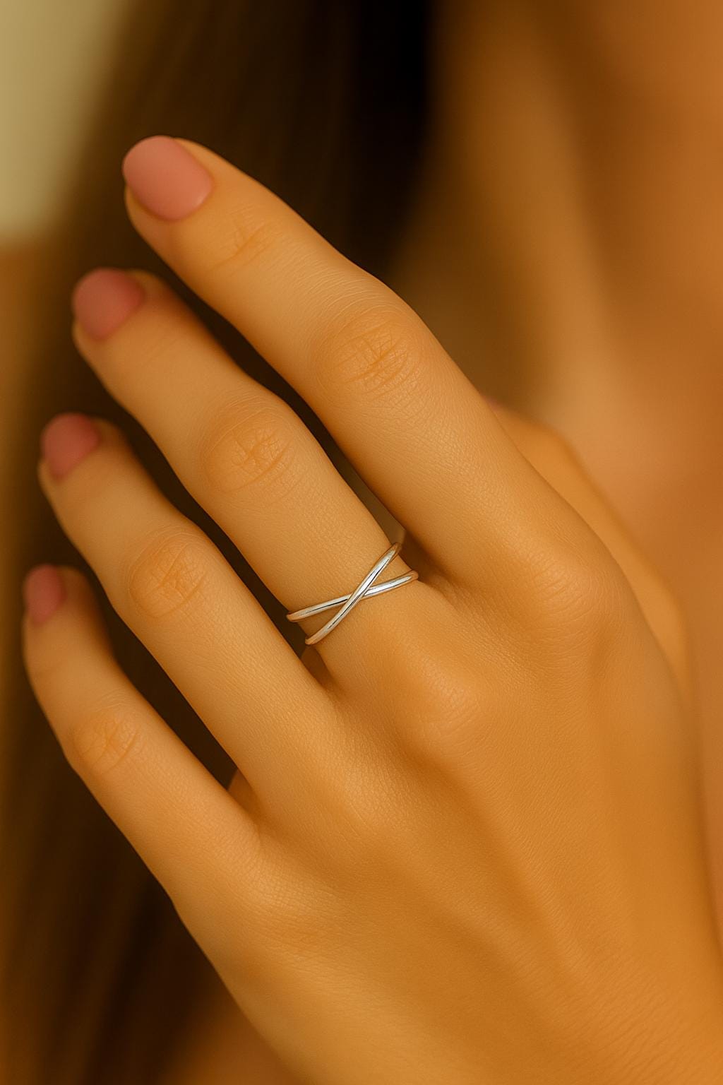 Hand wearing a silver ring with a blurred background