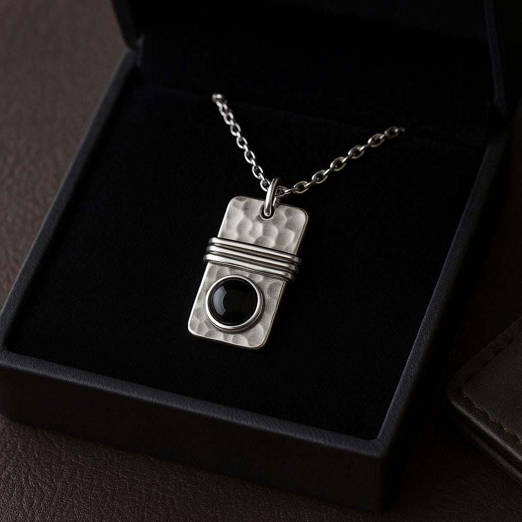 Silver pendant necklace with a black stone on a dark background