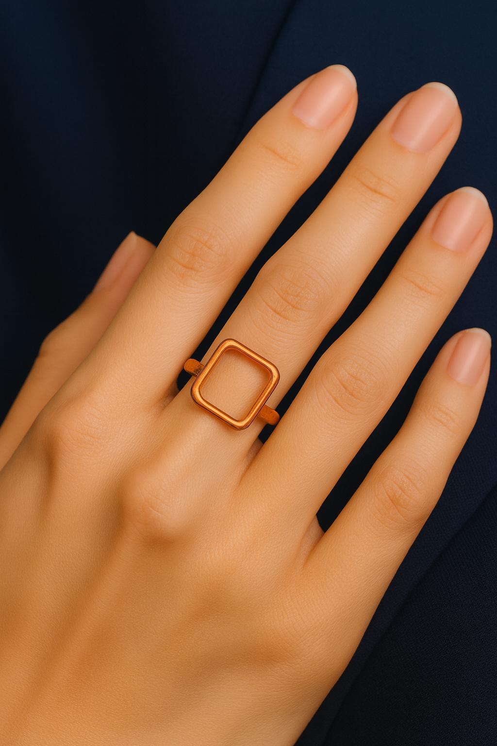 Hand wearing a gold square ring against a dark background
