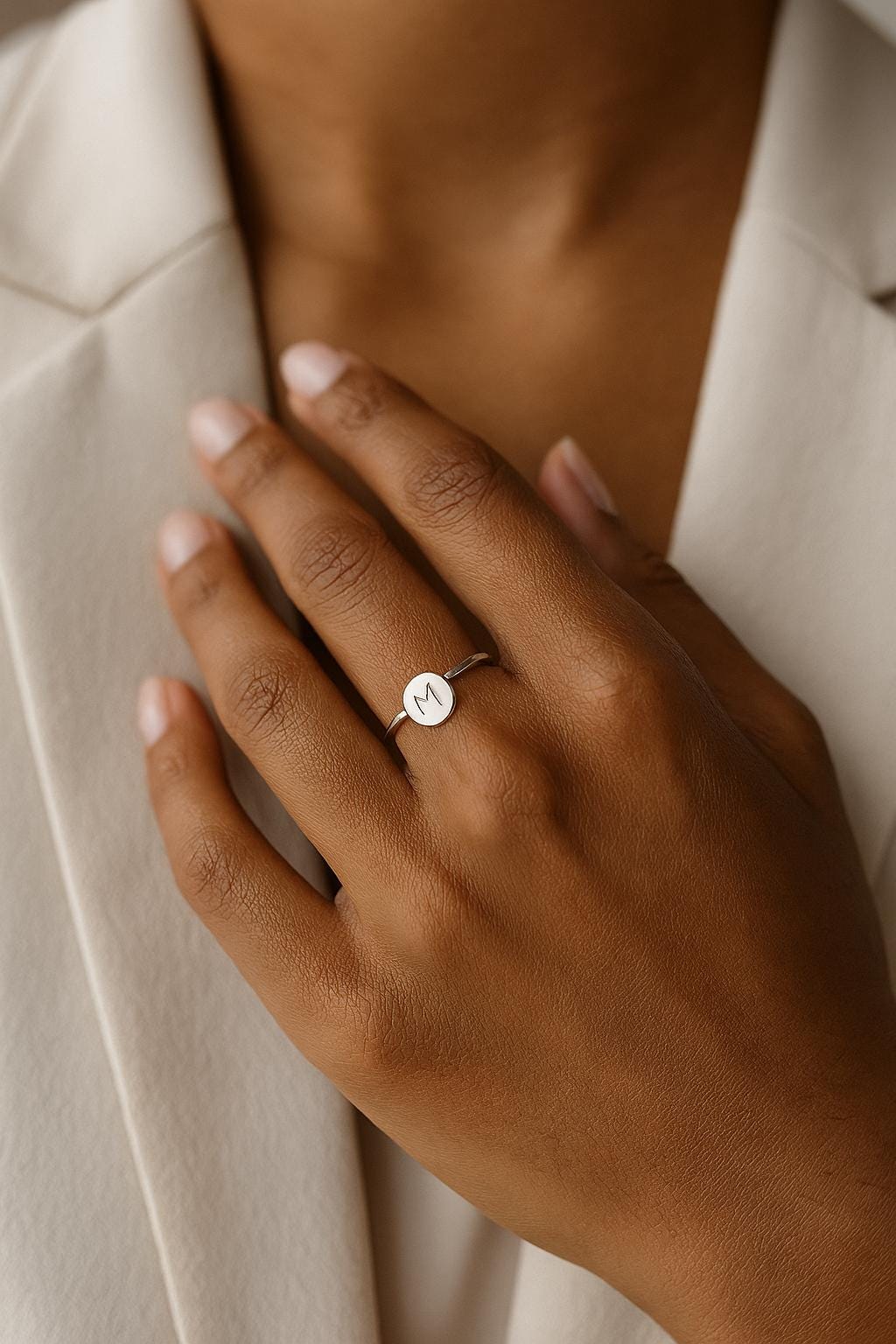 Hand wearing a silver ring with a small diamond on a neutral background