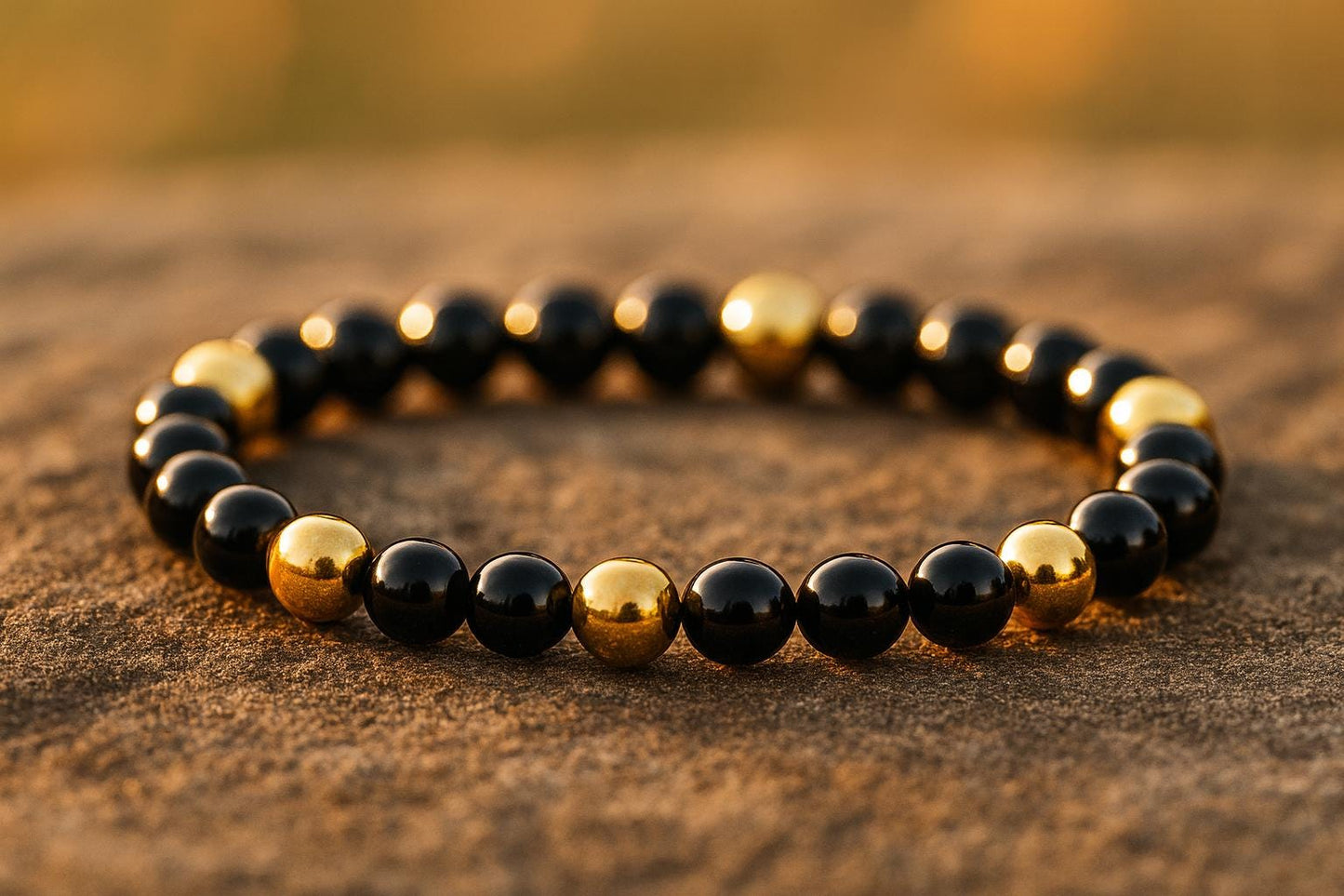 Black and gold beaded bracelet on a textured surface with a blurred background