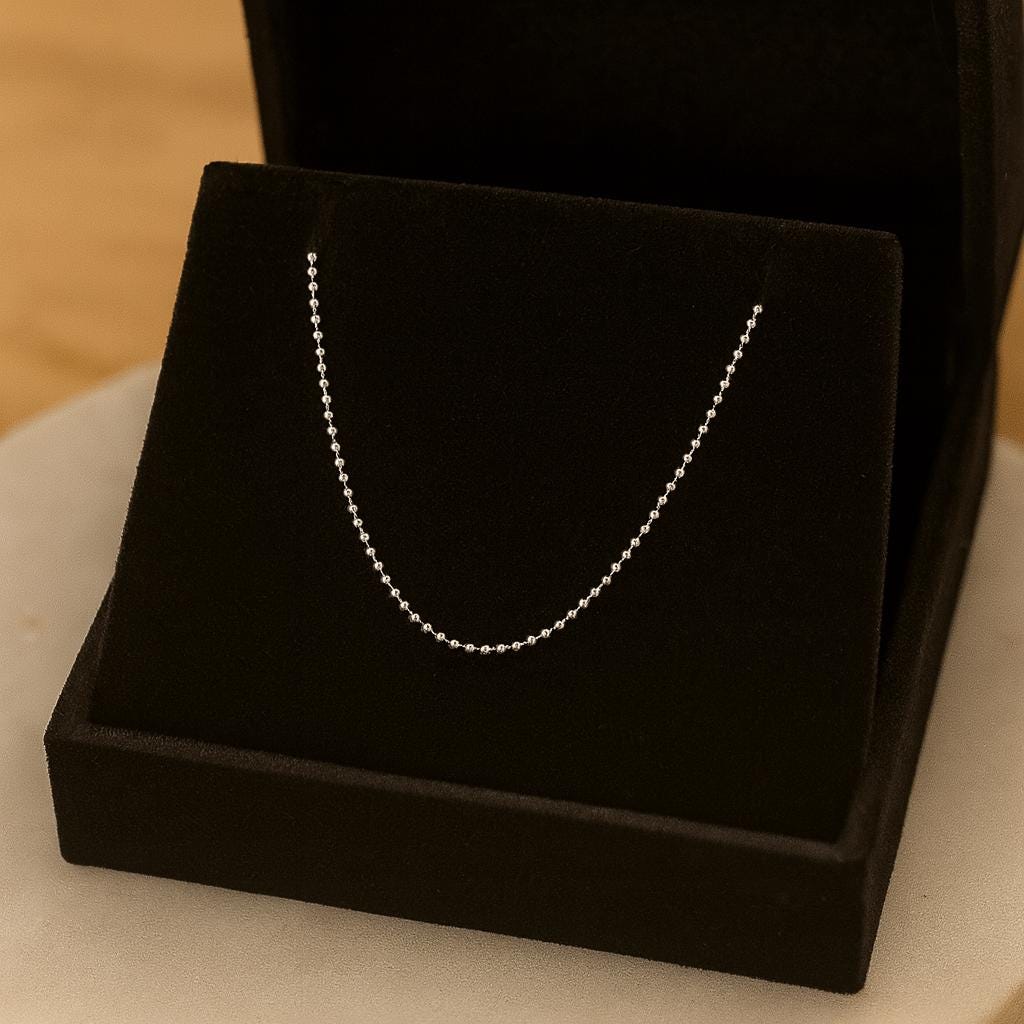 Silver chain necklace on a black velvet stand with a blurred background