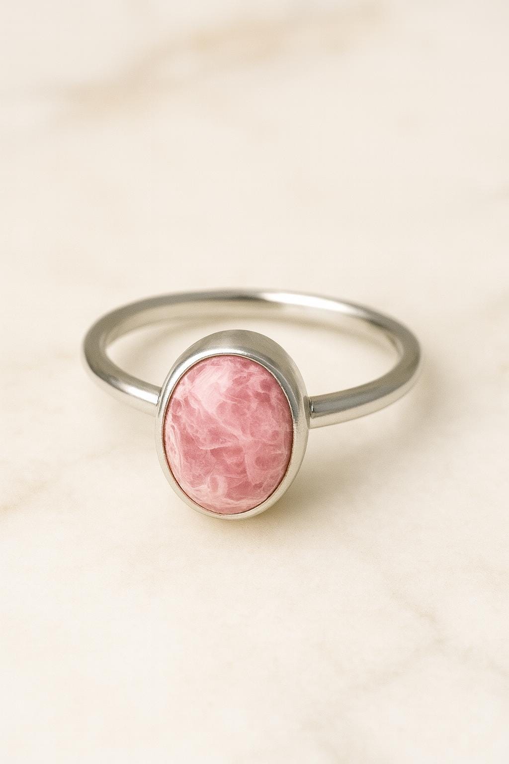 Silver ring with a pink stone on a beige background