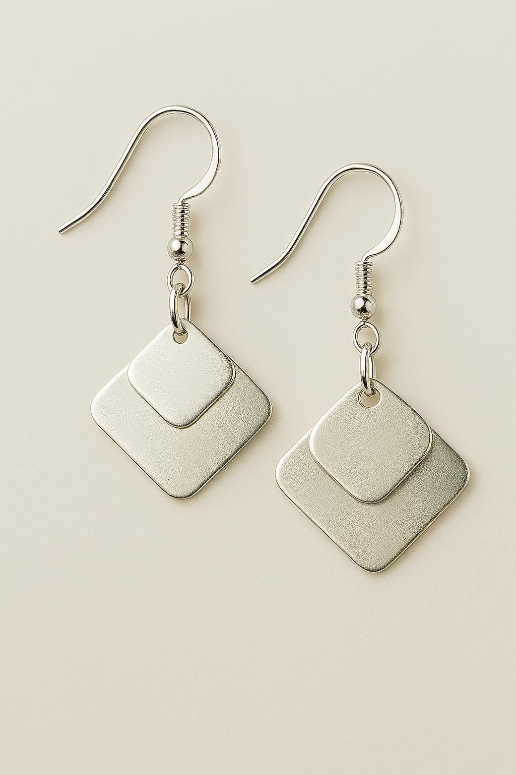 Pair of silver earrings on a beige background