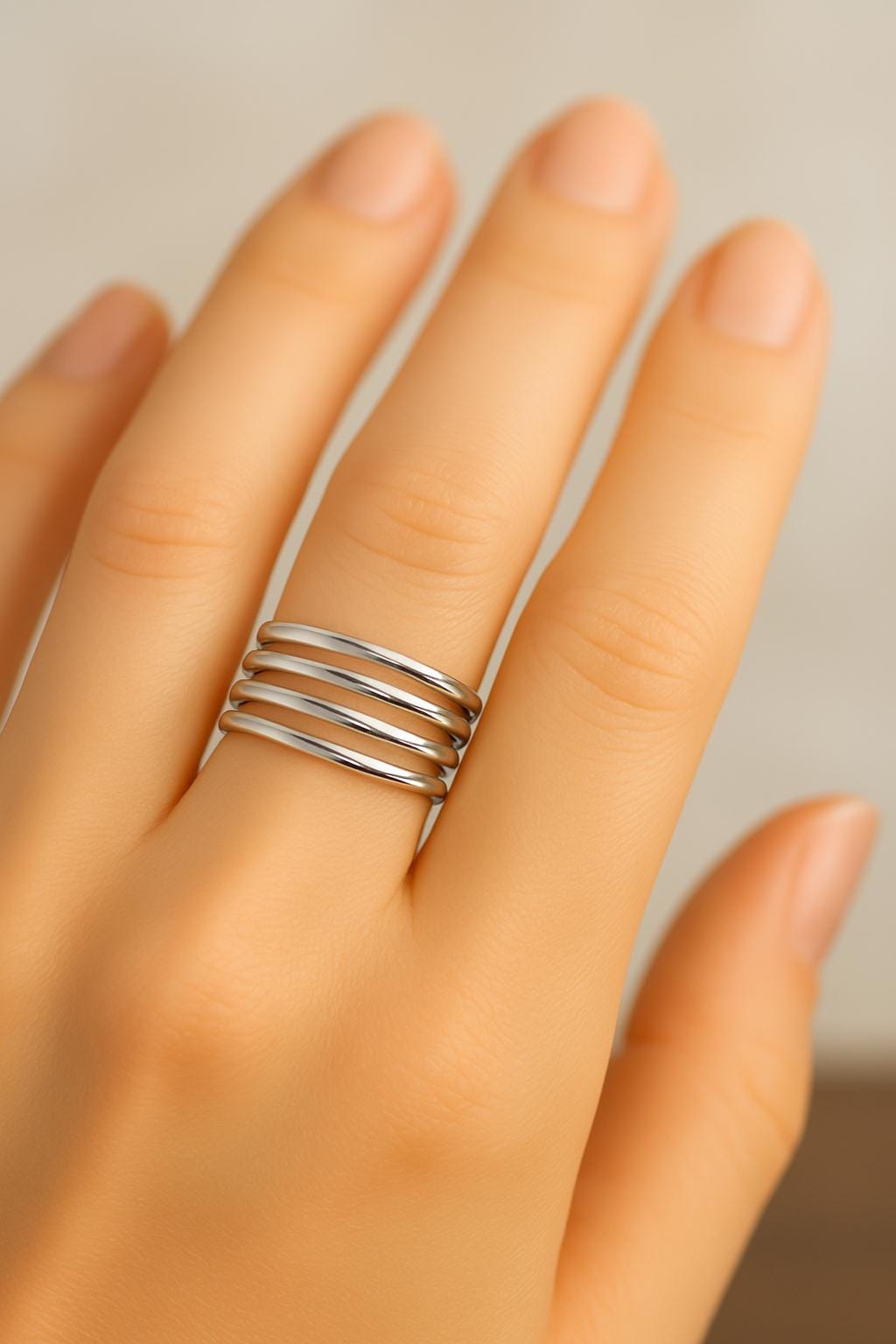 Silver ring on a finger against a neutral background