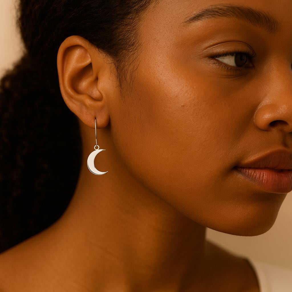 Close-up of a woman wearing a crescent moon earring with a warm-toned background