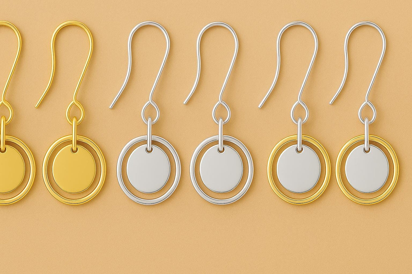 Pair of gold and silver earrings on a beige background