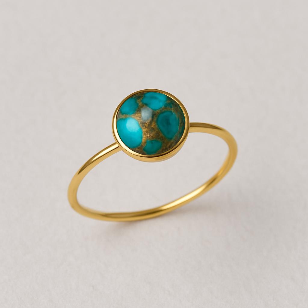 Gold ring with a turquoise stone on a light gray background