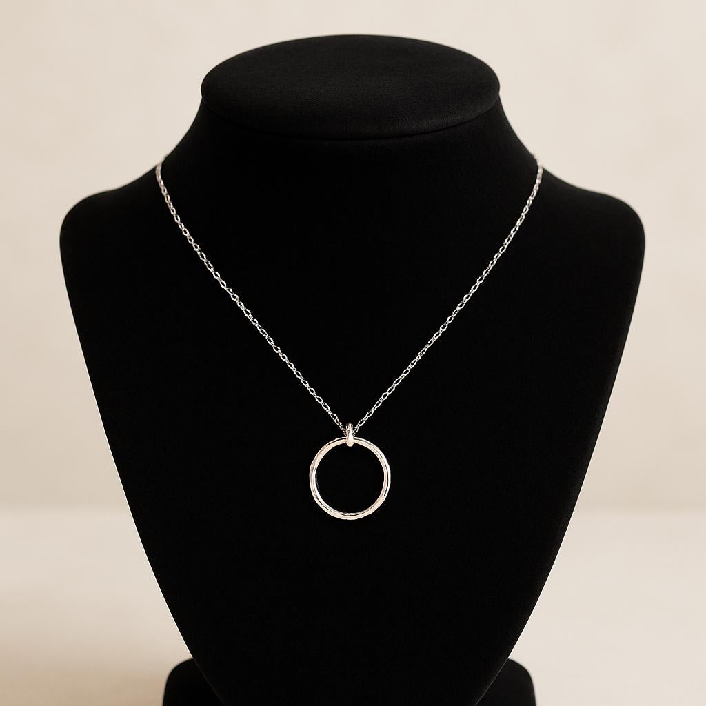 Silver necklace with a circular pendant on a black mannequin bust against a beige background