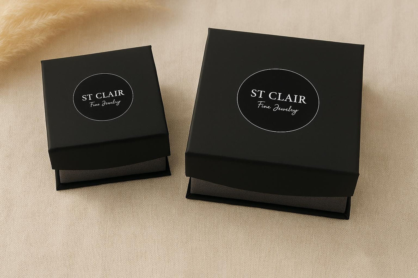 Two black jewelry boxes with 'St. Clair Fine Jewelry' logo on a beige surface