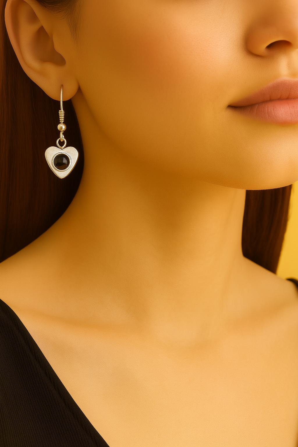 Heart-shaped earring with a black gemstone worn by a model