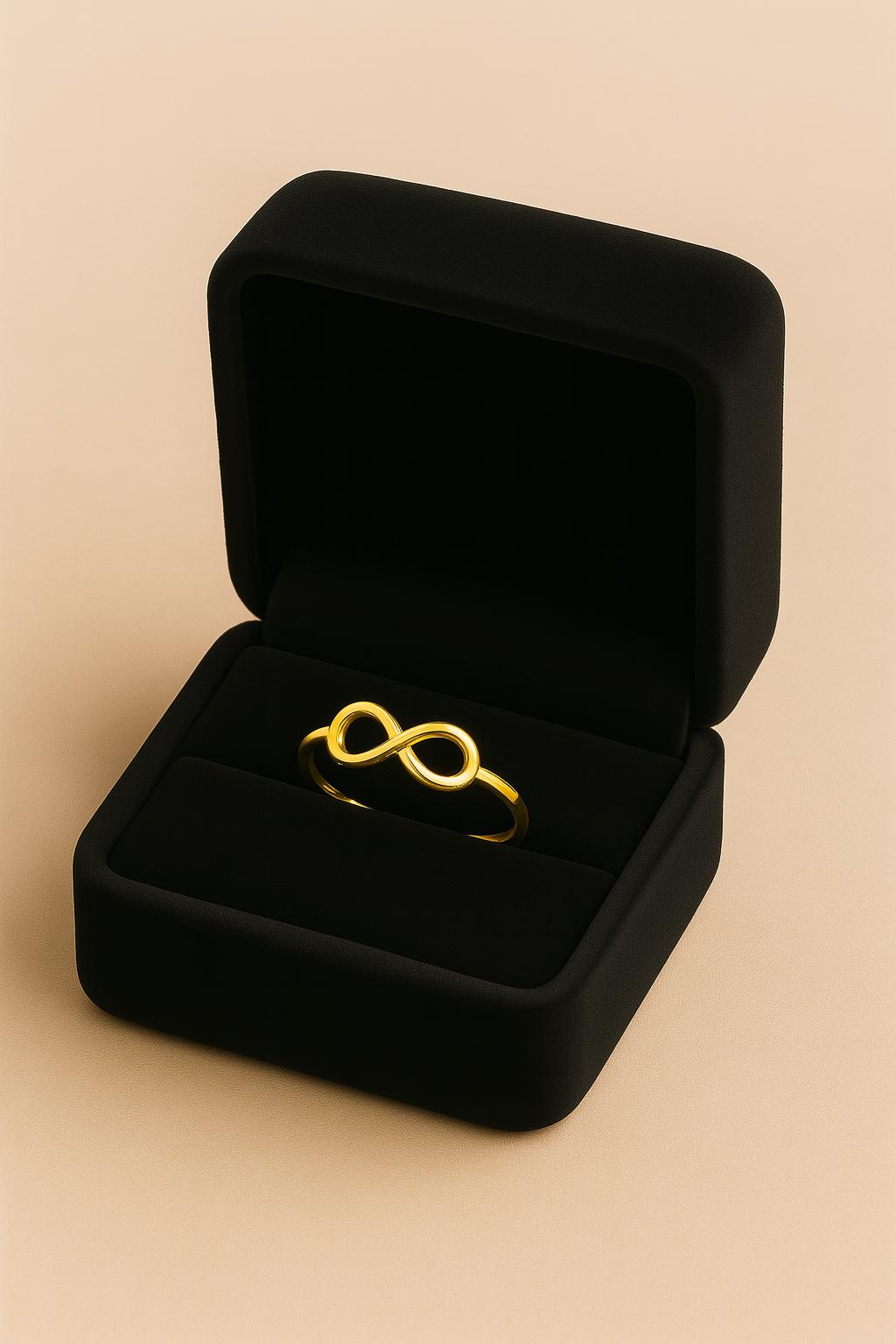 Gold infinity ring in a black jewelry box on a beige background