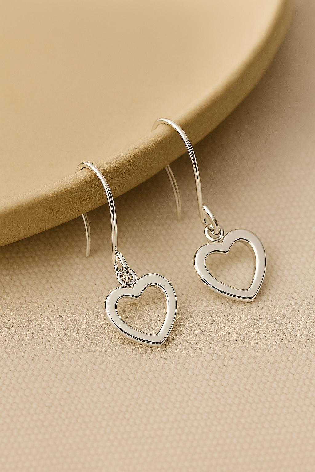 Silver heart-shaped earrings on a beige surface