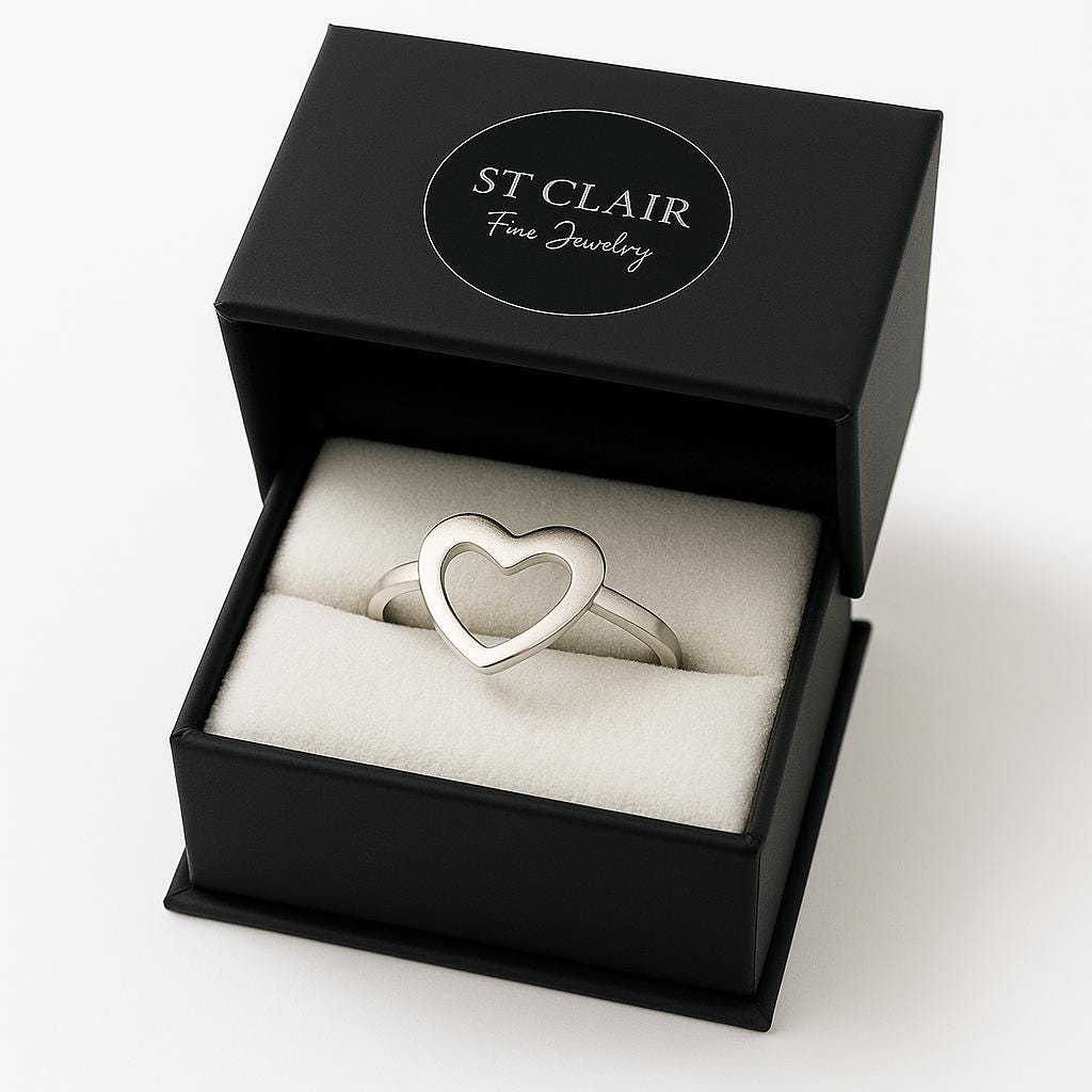 Silver heart-shaped ring in a black St. Clair Fine Jewelry box on a white background