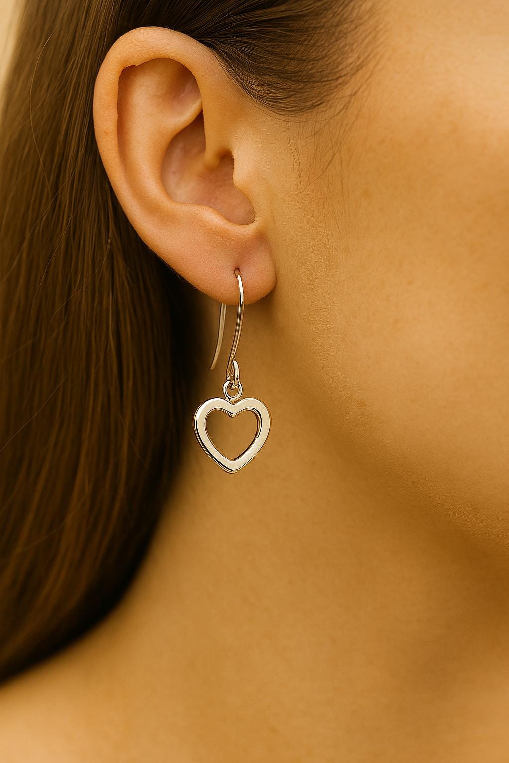 Heart-shaped earring worn by a person with brown hair.