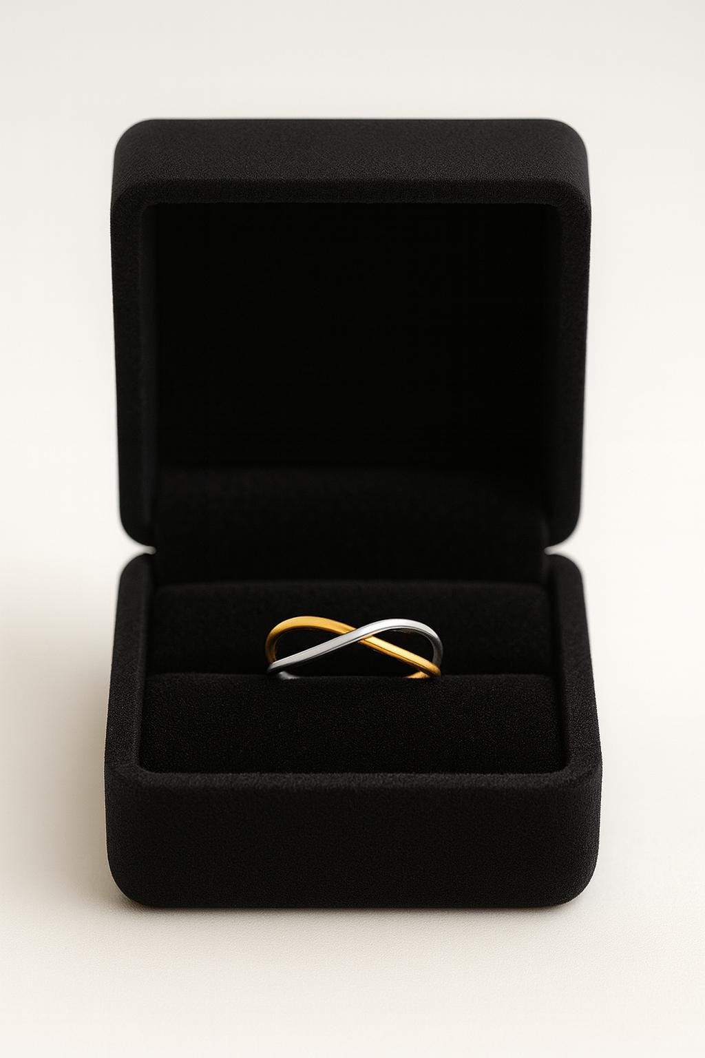 Two gold and silver infinity rings in a black jewelry box on a white background