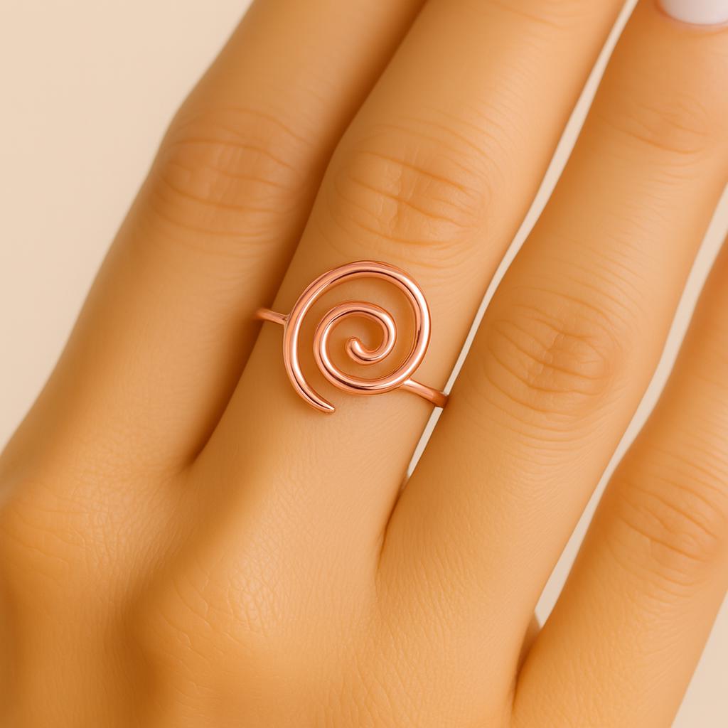 Rose gold spiral ring on a finger against a beige background
