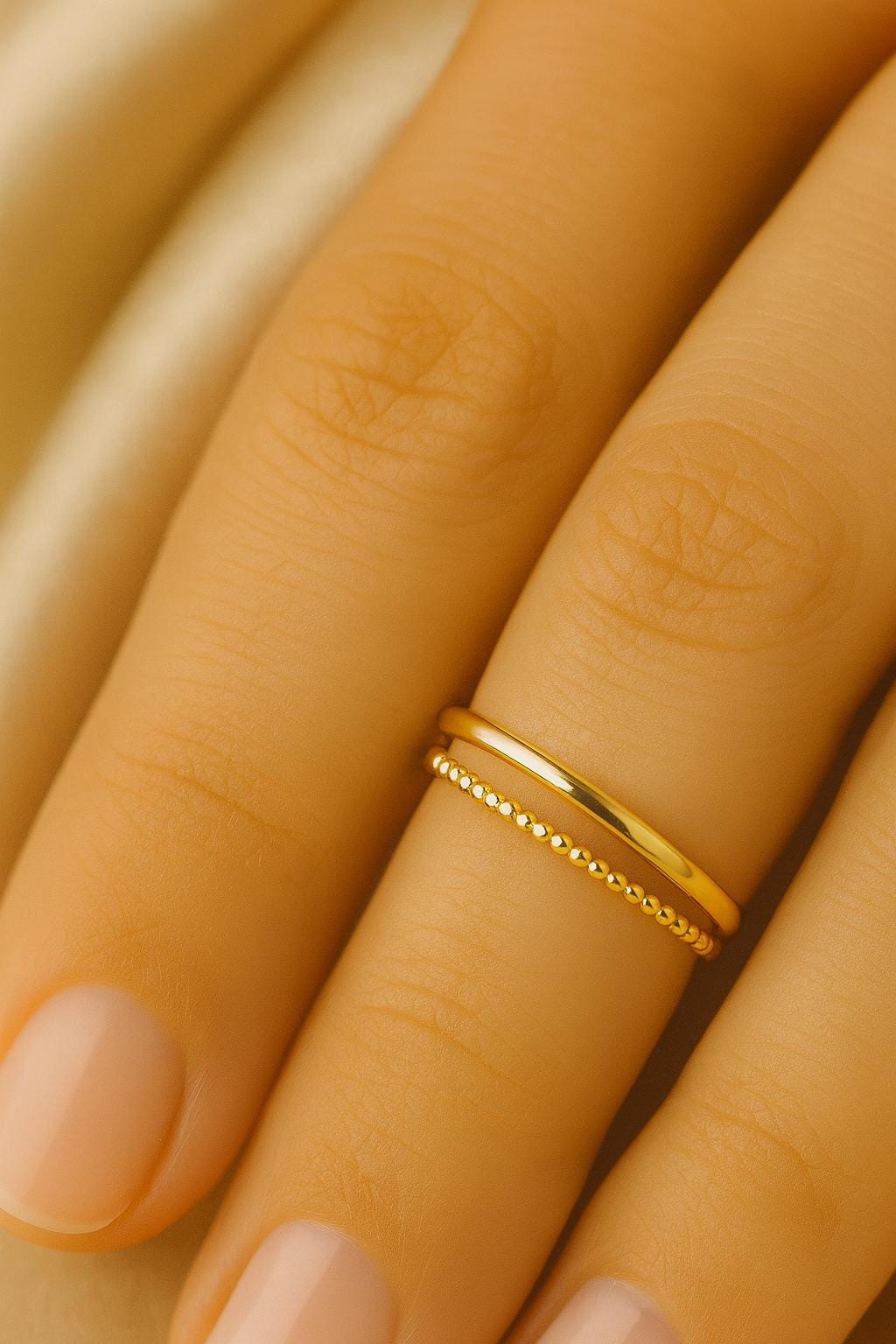 Gold ring on a person's finger with a warm background