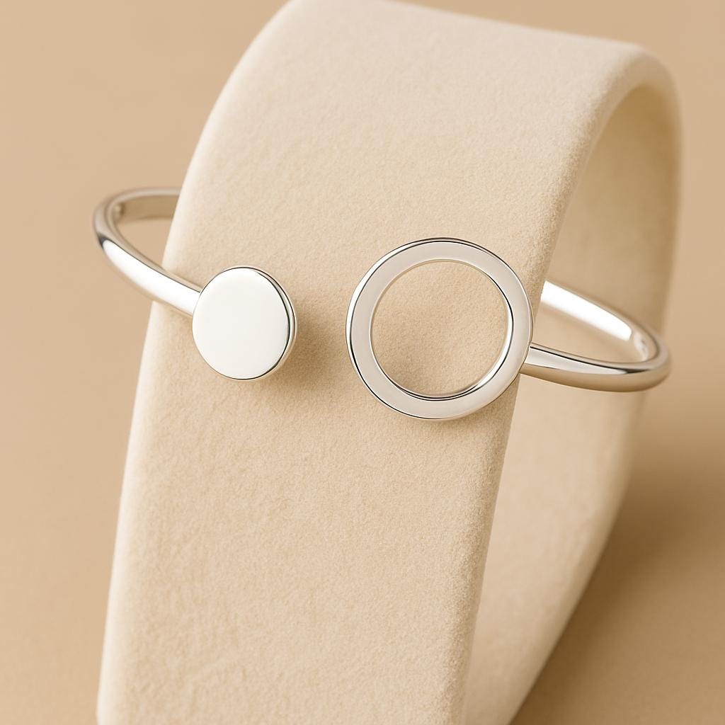 Silver bracelet with circular design on a beige fabric background