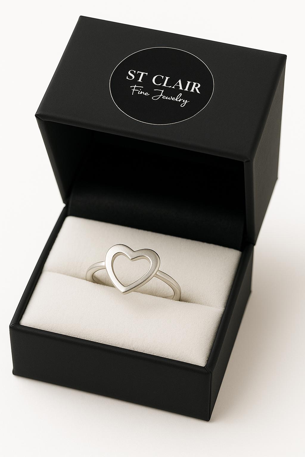Silver heart-shaped ring in a black St. Clair Fine Jewelry box on a white background