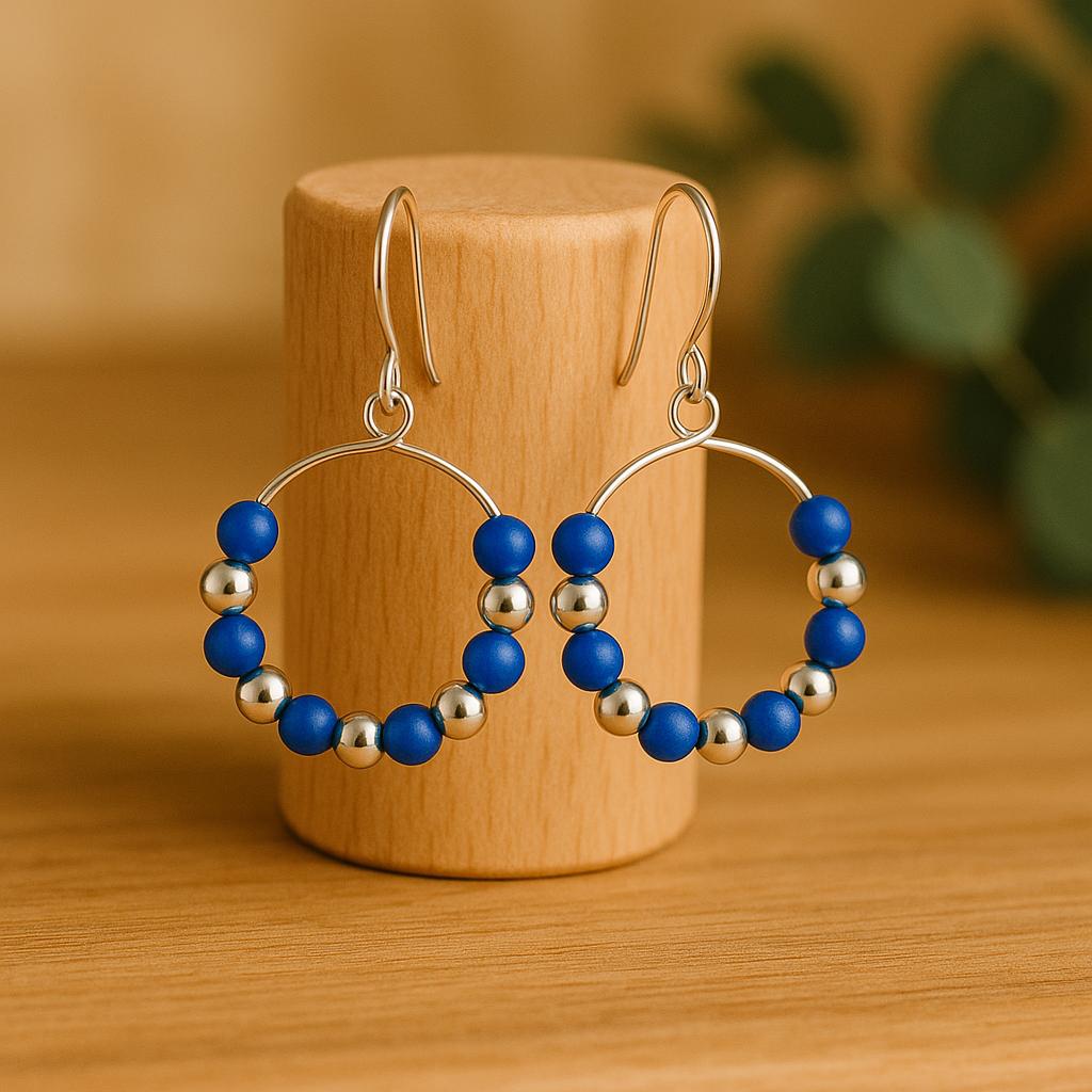Hoop earrings with blue and silver beads on a wooden stand.