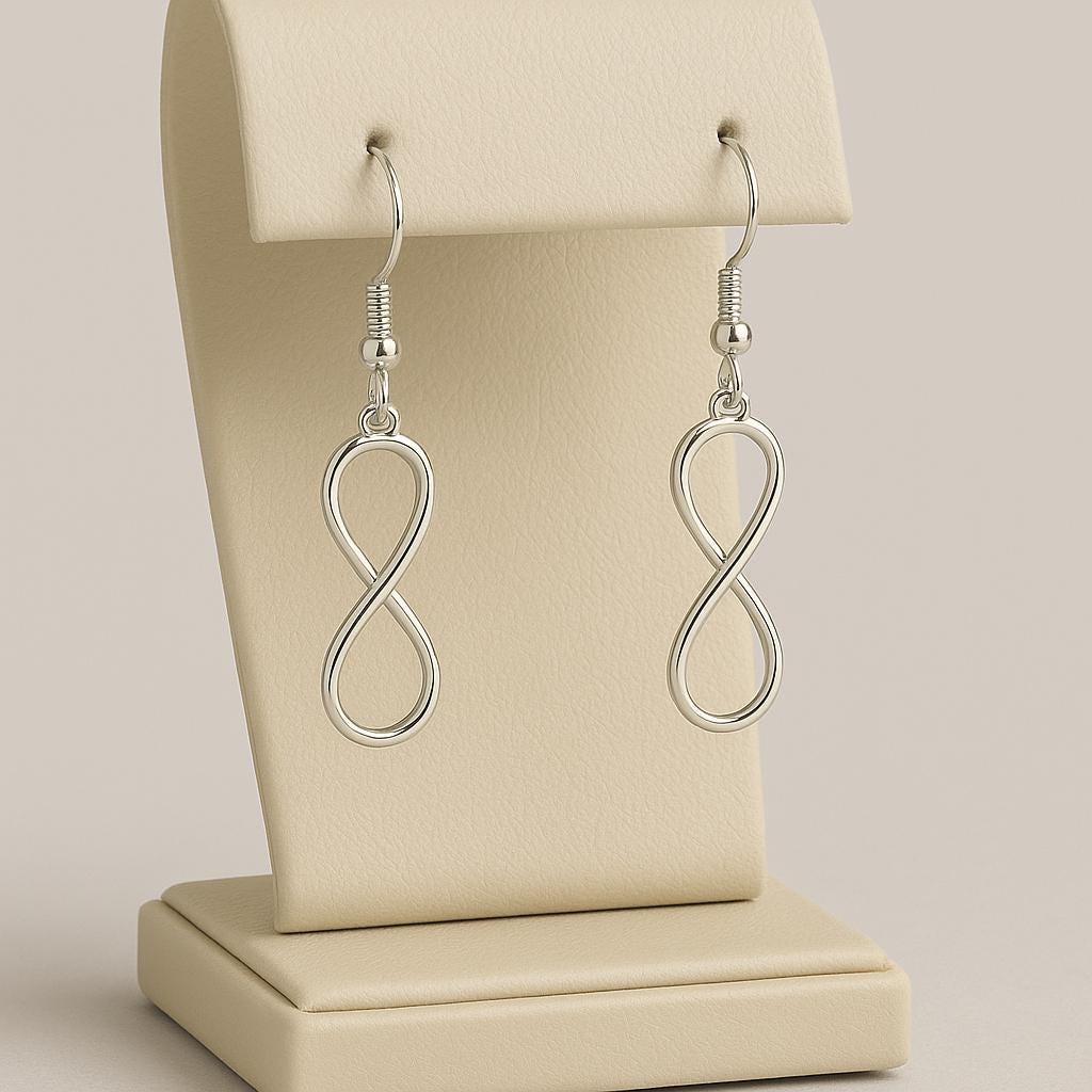 Silver infinity loop earrings on a beige earring stand.