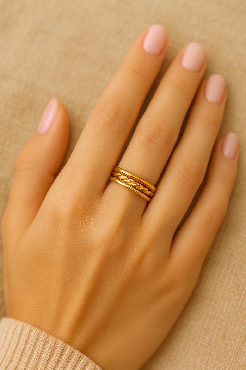 Gold ring on a hand against a beige background