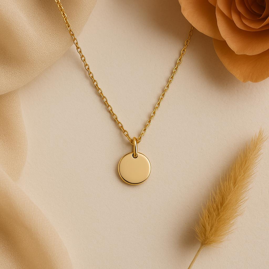 Gold necklace with a round pendant on a beige background with flowers and grass.
